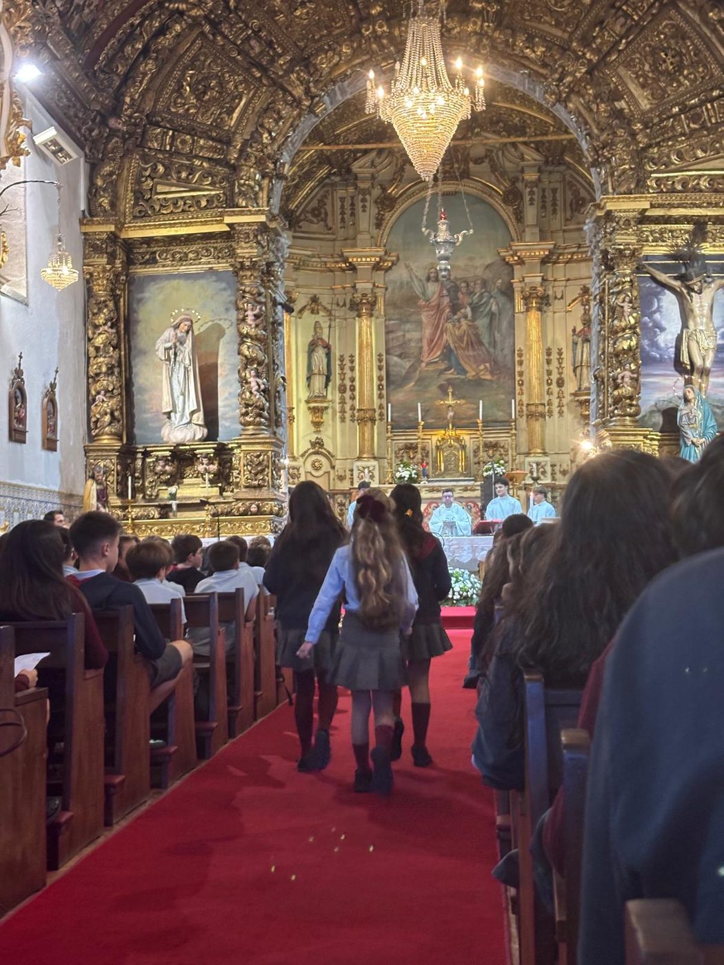 Alunos a caminhar pelo corredor central da igreja em direção ao altar